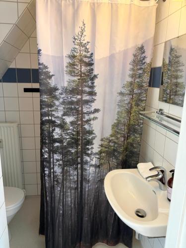 a bathroom with a shower curtain with a forest at Huset ved springvandet in Randers