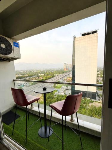 a balcony with two chairs and a table and a view at ELYSIUM TOWER- One Bedroom Luxury Apartment With Balcony & City View OPP Centaurus Mall Islamabad in Islamabad
