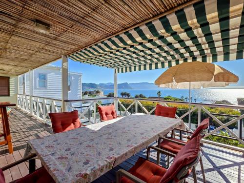 a table with chairs and an umbrella on a balcony at Eindelik in Simonʼs Town