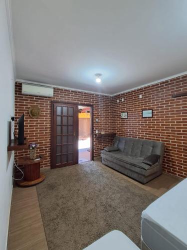 a living room with a couch and a brick wall at Espaço Gozzoli, Cantinho da Nonna in Espirito Santo Do Pinhal