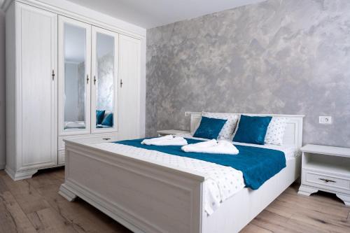 a white bedroom with a blue and white bed at Casa Agigea in Agigea