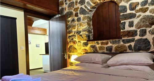 a bed in a room with a stone wall at Palatino Seafront Residence in Alinda