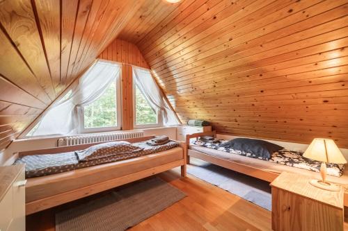 two beds in a room with a wooden ceiling at Sanjska Hiša Vojsko in Idrija