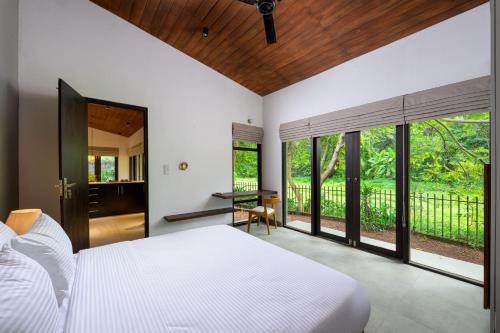 a bedroom with a bed and a desk and windows at The Plunge by Duo Escapes in Gonahena