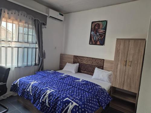 a bedroom with a bed with a blue comforter at D-vine Apartments & Hotels in Benin City