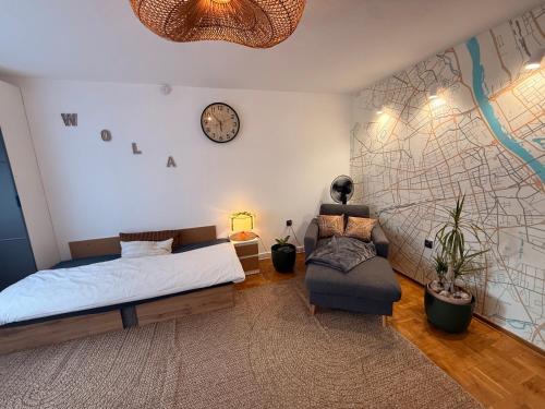 a bedroom with a bed and a chair and a clock at Sloth Room in Warsaw