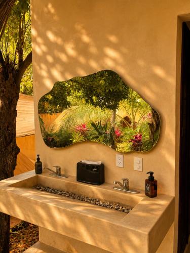 a bathroom with a sink with a painting on the wall at Shamalay - Nomad Experience in Bacalar