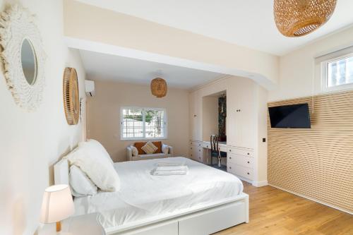 a white bedroom with a bed and a tv at New Horizon Algarve in Almancil