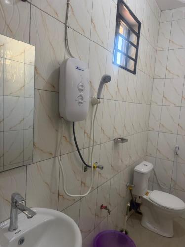 a bathroom with a sink and a toilet and a window at Angels Lodge in Dar es Salaam