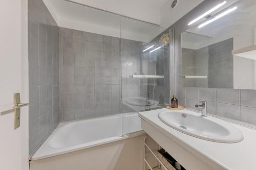 a white bathroom with a tub and a sink at Charmant appartement proche Val Europe Disneyland paris in Torcy