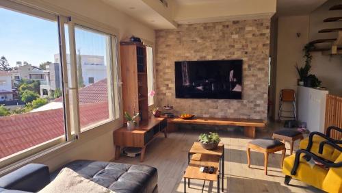 a living room with a tv on a brick wall at Gador Sea View in H̱adera
