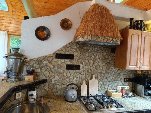 a kitchen with a stove and a stone wall at Jumpravmuižas pirtiņa ar kublu in Mežotne
