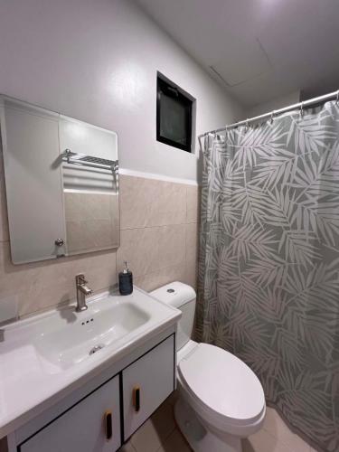 a bathroom with a toilet and a sink and a shower at Cozy Crib at Royal Oceancrest Mactan in Mactan Island