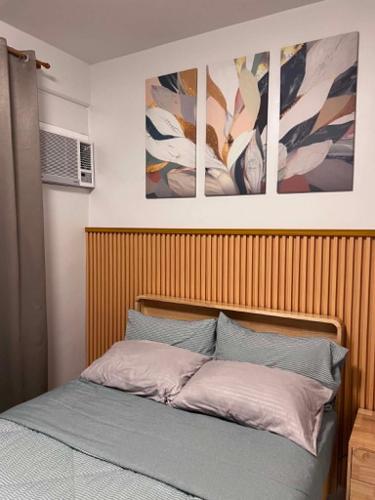 a bedroom with a bed with three paintings on the wall at Cozy Crib at Royal Oceancrest Mactan in Mactan Island