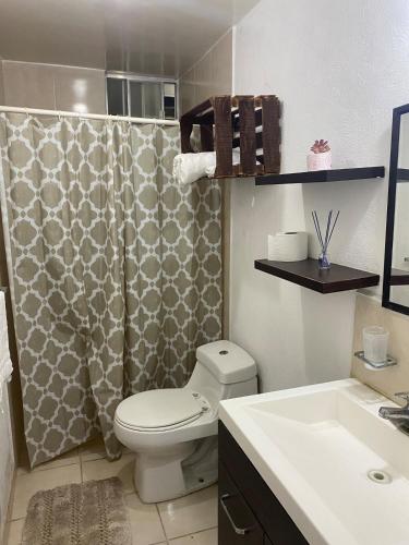 a bathroom with a toilet and a shower curtain at Ruah Home in Guadalupe