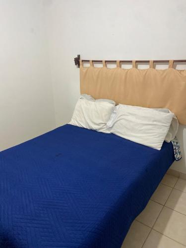 a bed with blue sheets and white pillows at Ruah Home in Guadalupe