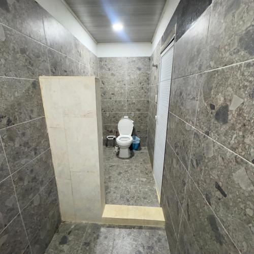 a bathroom with a toilet and a tiled wall at Hotel Habitaciones D y Mar in Tolú