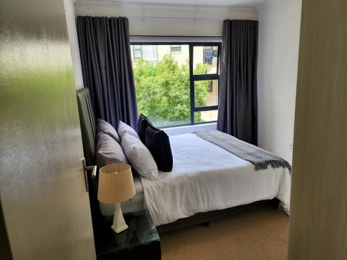 a bedroom with a bed and a large window at Comfort & Style at the Ihita Complex - Beverley, Sandton in Sandton
