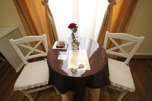 a round table with two chairs and a vase with flowers at Freedom Love B&B in Rome