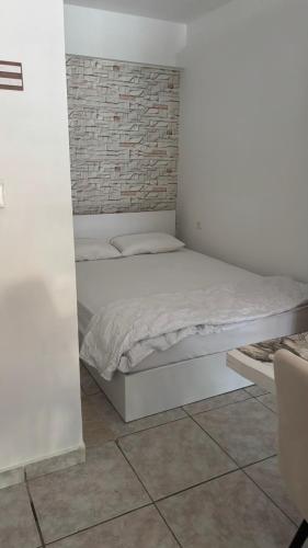 a white bed in a room with a brick wall at Olimpik bic in Paralia Katerinis
