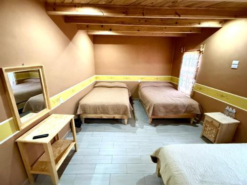 a room with three beds and a mirror at Hotel Nuevo Amanecer in Real de Catorce
