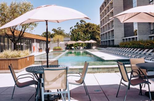 a pool with tables and chairs and an umbrella at Resort com Piscina Aquecida e Garagem em Xangri-lá in Xangri-lá
