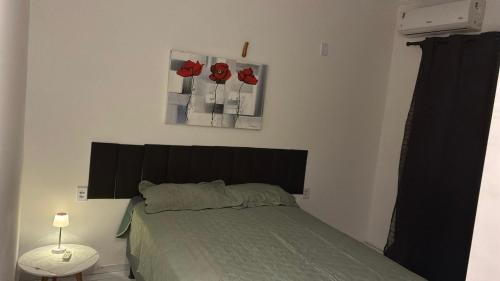 a bedroom with a bed with red flowers on the wall at Pousada Apart Praia Uruaú in Beberibe