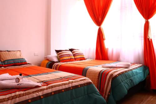 two beds in a room with a window at Hotel Inkanta in Ipiales