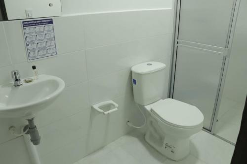 a white bathroom with a toilet and a sink at Hotel Inkanta in Ipiales