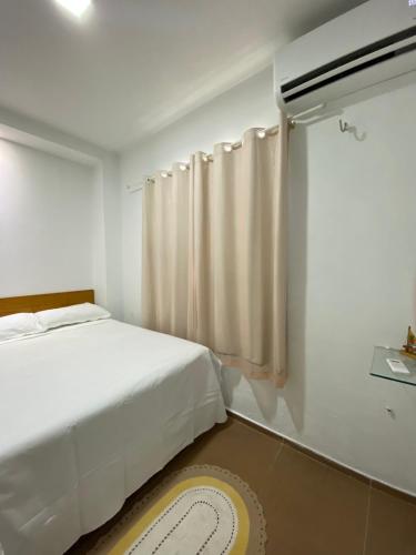 a white bedroom with a bed and a window at Green duplex cottage in Camocim in Camocim