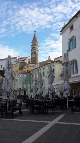a group of tables with umbrellas and a clock tower at Holiday Home Amazing View in Piran