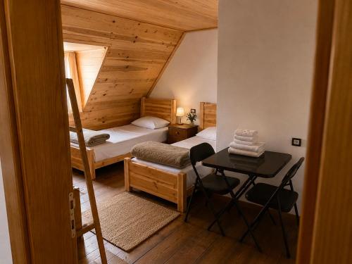 a bedroom with two beds and a table and a desk at Guesthouse Pashko in Theth