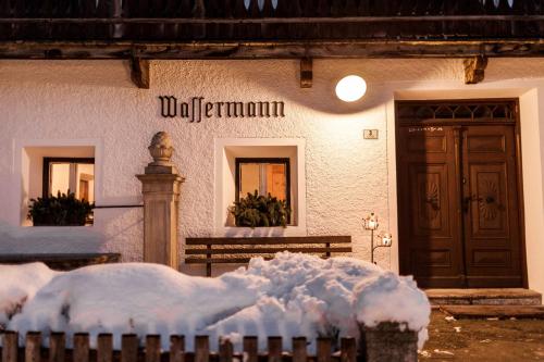a building covered in snow with a bench in front of it at Wassermann in Sesto