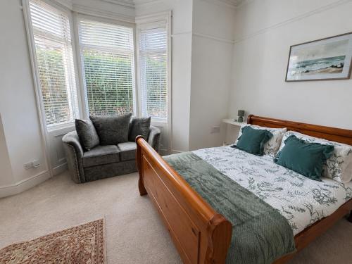 a bedroom with a bed and a chair and windows at Queenie's Nook in North Shields