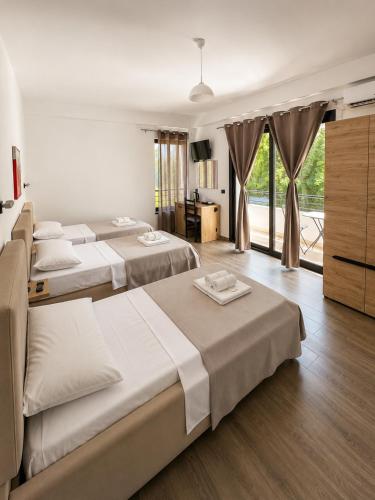 a hotel room with three beds and a television at Lungomare private rooms in Vlorë