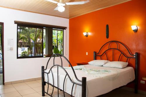 a bedroom with a bed with an orange wall at Hotel D'Lucia - Quebrada Ganado, Jaco, Costa Rica in Puntarenas