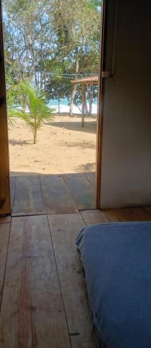 an open door to a room with a bed and the beach at FOLHA HOUSE Experience in Paraty