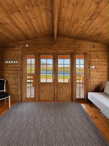 a living room with wooden walls and a couch and windows at Hotel Stadarborg in Breiðdalsvík