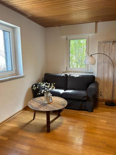 a living room with a black couch and a table at Fewo kleine Auszeit in Karbach