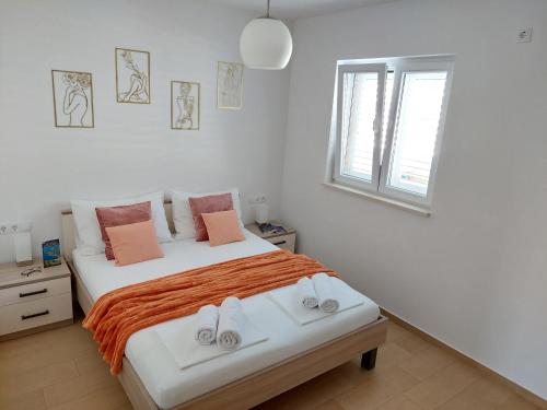 a white bedroom with a large bed with orange sheets at Slano Bay Apartments in Slano