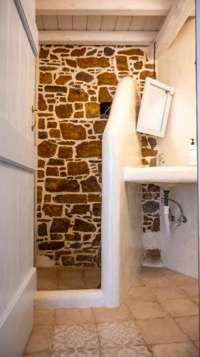 a bathroom with a stone wall and a sink at Rodakas Rooms-Dafni in LivadhokhÃ³rion
