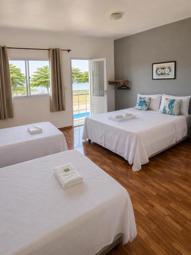 a hotel room with two beds and a balcony at Pousada Sol & Mar Jacaraìpe ES in Serra