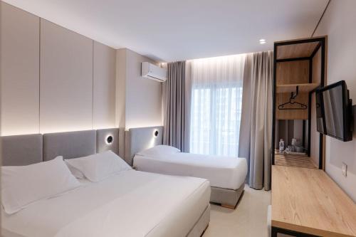 a hotel room with two beds and a television at Hotel Mediterrane in Sarandë