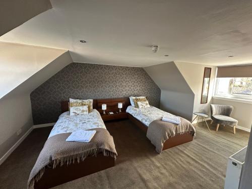 a attic room with two beds and a window at Rooms at 31 in Stonehaven