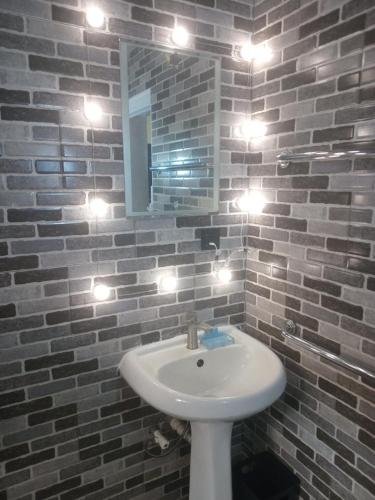 a bathroom with a sink and lights on a brick wall at The Close in Asaba