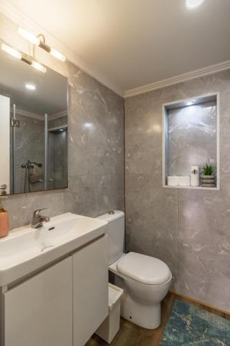 a bathroom with a toilet and a sink and a mirror at Alma do Bairro in Lisbon