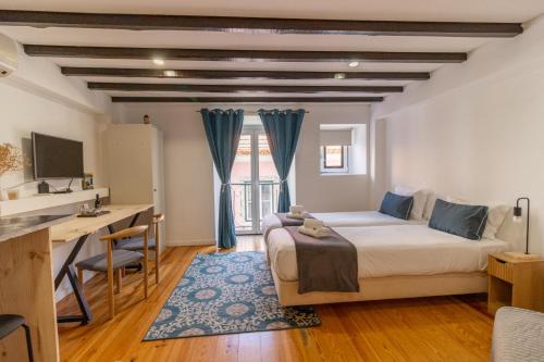a bedroom with a bed and a desk and a computer at Alma do Bairro in Lisbon