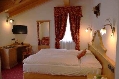 a hotel room with a bed and a window at Hotel Pordoi - Fam Furgler in Arabba