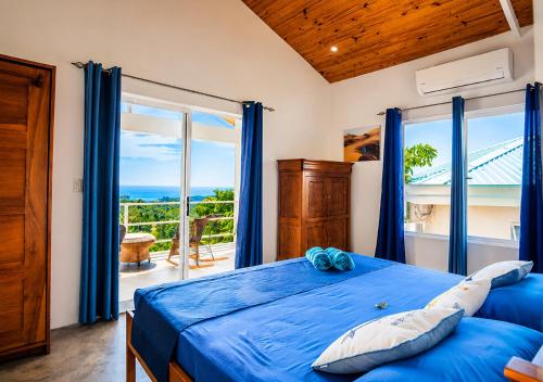 a bedroom with a blue bed with a view of the ocean at Lodge Las Estrellas de Samara - Ocean View in Sámara