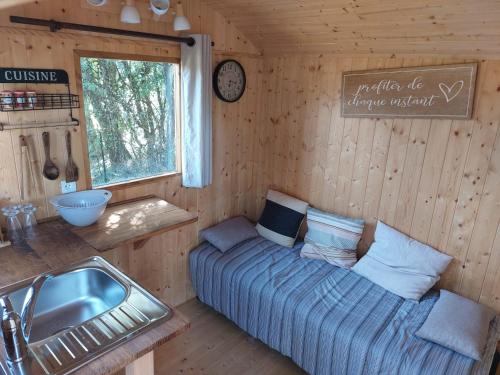 a room with a couch and a sink in a cabin at La roulotte enchantée in Le Boissenet